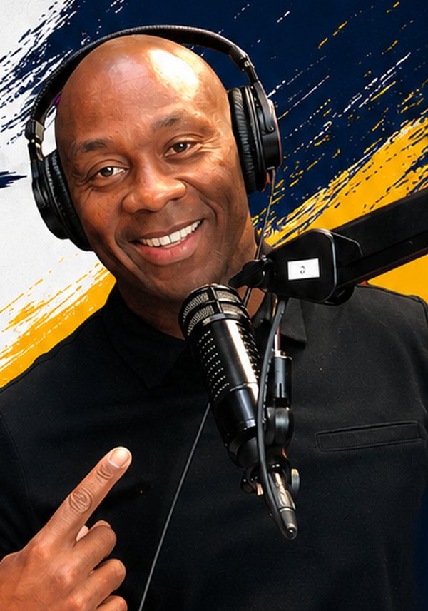 DeVone Holt in the studio wearing headphones at a broadcast microphone
